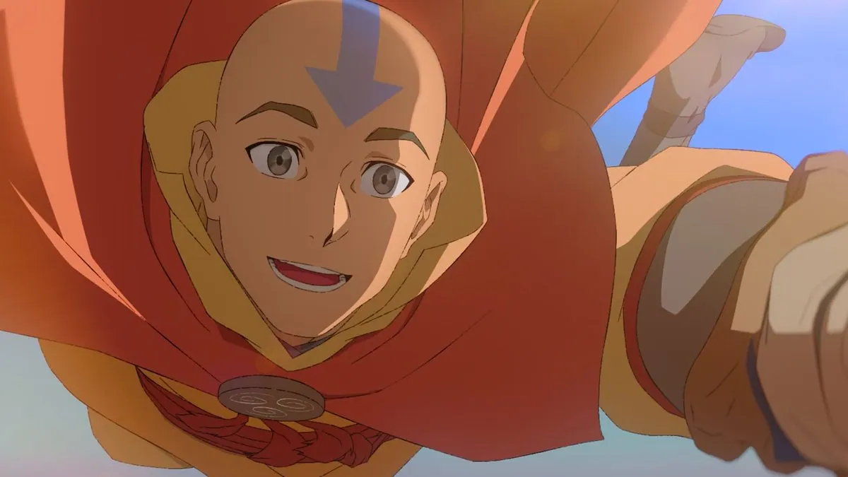 First-look still of a smiling adult Aang flying toward the camera, reaching out, red cape billowing
