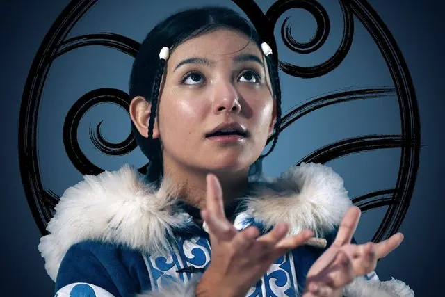 Season 1 character portrait: Kiawentiio as Katara in a fur-trimmed parka in front of the Water Tribe emblem