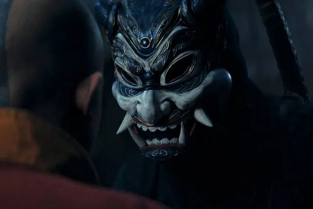 Season 2 still: a figure in a blue oni mask confronting Aang in darkness
