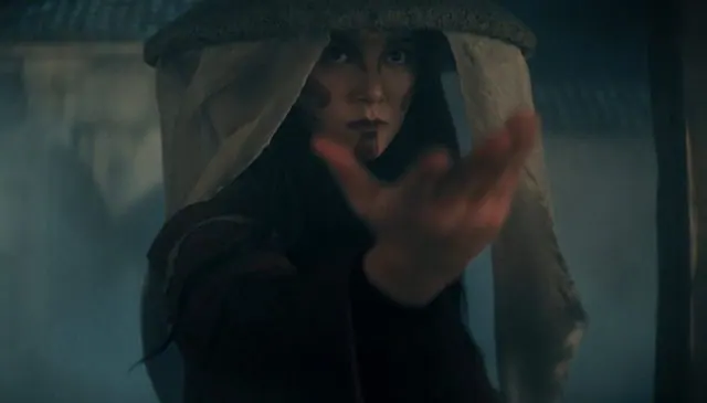 Season 2 still: Kiawentiio as Katara in a veiled hat (the Painted Lady) reaching out through mist