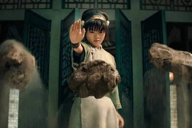 Season 2 still: Toph earthbending and levitating boulders in front of green doors
