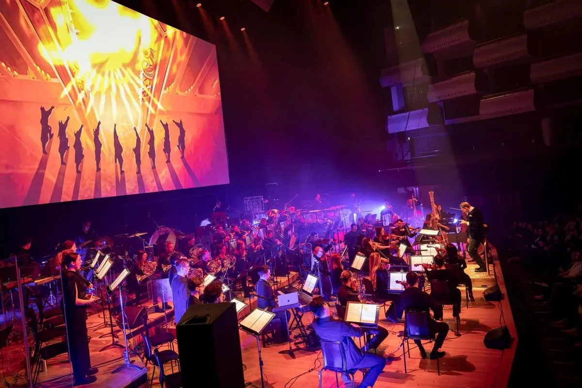 Orchestra bathed in red-orange light while a firebending scene plays on screen, Avatar: The Last Airbender in Concert