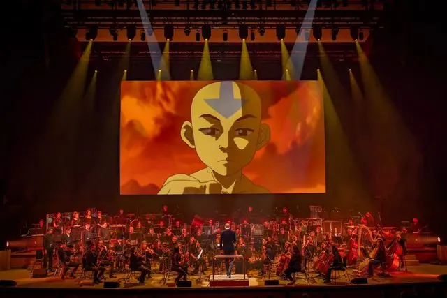 Live orchestra on stage under spotlights with Aang projected on the cinema screen, Avatar: The Last Airbender in Concert