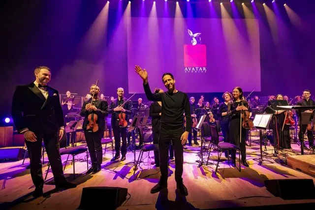 Musicians and conductor taking a bow under purple lights at the end of Avatar: The Last Airbender in Concert